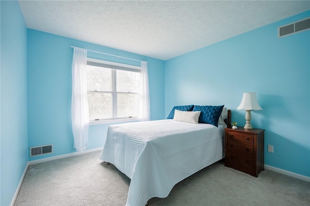 carpeted bedroom featuring a textured ceiling, baseboards, and visible vents