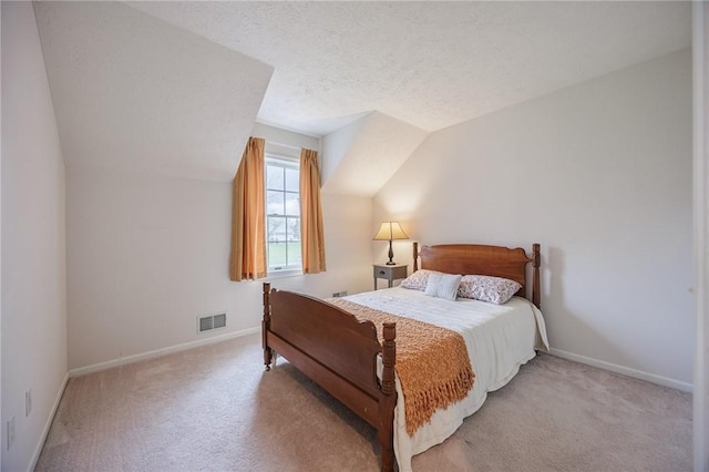 bedroom with lofted ceiling, a textured ceiling, baseboards, visible vents, and light carpet