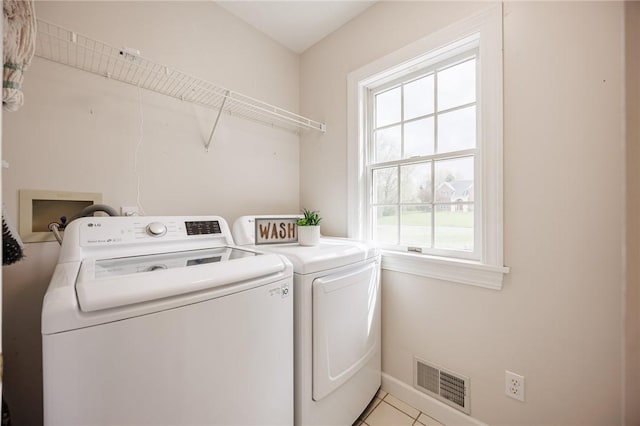 washroom featuring washer and clothes dryer, laundry area, visible vents, light tile patterned floors, and baseboards