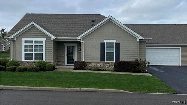 craftsman-style house featuring stone siding, roof with shingles, driveway, and a front lawn