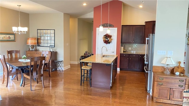 kitchen featuring dark wood-style flooring, a sink, a chandelier, tasteful backsplash, and appliances with stainless steel finishes