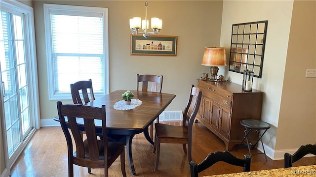 dining area with an inviting chandelier, light wood-type flooring, visible vents, baseboards, and plenty of natural light
