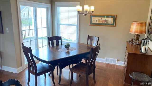 dining area featuring an inviting chandelier, wood finished floors, visible vents, and baseboards