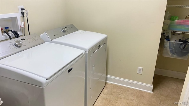 washroom featuring light tile patterned floors, laundry area, washing machine and dryer, and baseboards