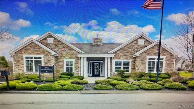view of front of property with stone siding and a chimney