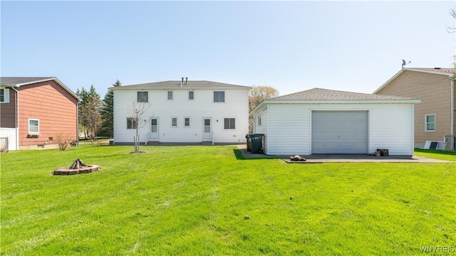 rear view of property with an outdoor fire pit, an outdoor structure, a garage, and a lawn