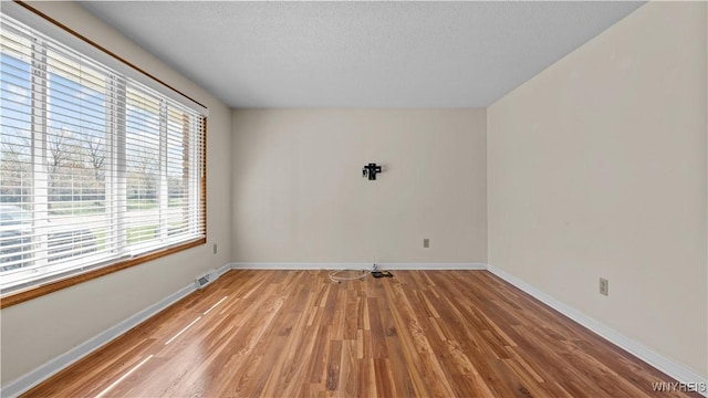 unfurnished room with baseboards, light wood-type flooring, and visible vents