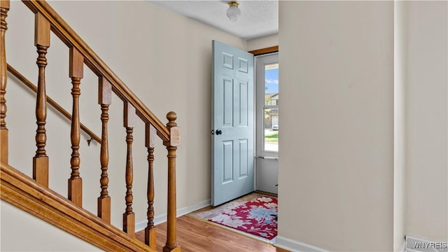 entrance foyer featuring stairway, light wood-style flooring, and baseboards