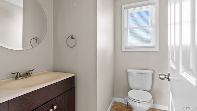 bathroom featuring toilet, baseboards, and vanity