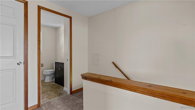 hall featuring carpet floors, baseboards, and an upstairs landing