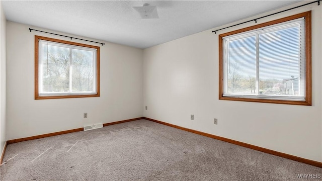 empty room featuring baseboards, visible vents, and carpet floors