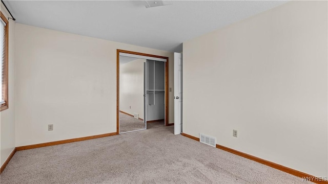 carpeted empty room featuring visible vents and baseboards
