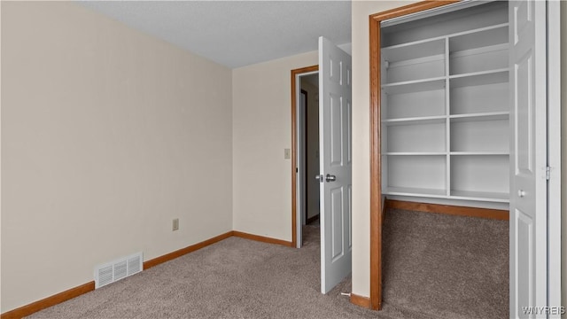 unfurnished bedroom with a closet, visible vents, baseboards, and carpet floors
