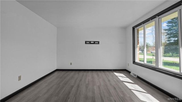 spare room featuring baseboards, visible vents, and wood finished floors