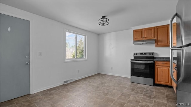 kitchen featuring brown cabinetry, visible vents, under cabinet range hood, dark countertops, and appliances with stainless steel finishes