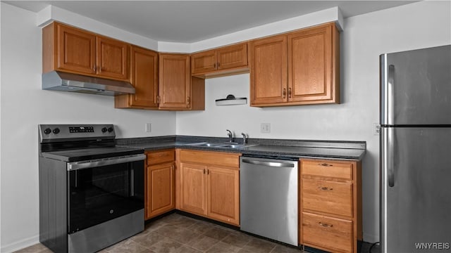 kitchen with under cabinet range hood, a sink, brown cabinets, dark countertops, and stainless steel appliances