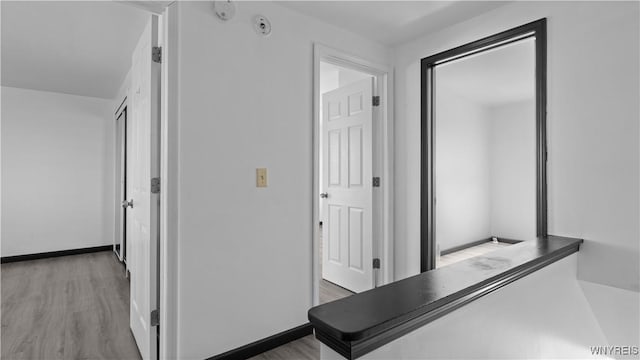 hall with baseboards and wood finished floors