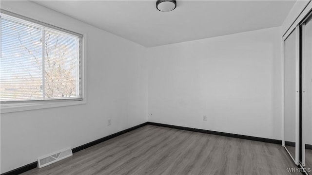 unfurnished bedroom featuring a closet, light wood-type flooring, visible vents, and multiple windows