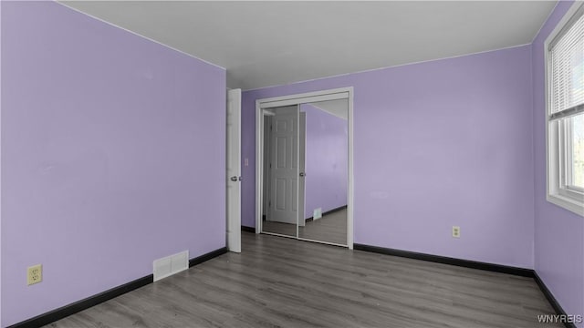 unfurnished room featuring visible vents, wood finished floors, and baseboards
