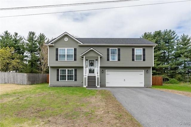 bi-level home with a front lawn, driveway, fence, and a garage