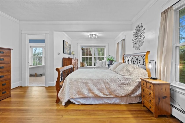 bedroom featuring crown molding, light wood-type flooring, baseboard heating, and multiple windows