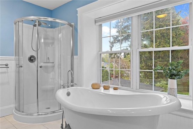 bathroom with a shower stall, tile patterned floors, a soaking tub, and a wainscoted wall