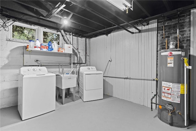 washroom featuring washing machine and clothes dryer, a sink, gas water heater, and laundry area
