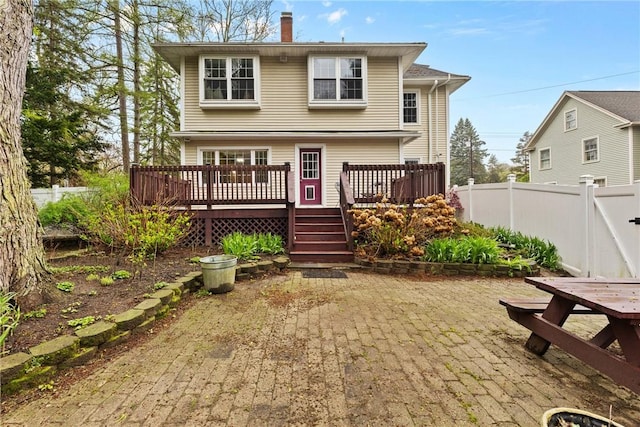 rear view of house with a chimney, fence, and a deck