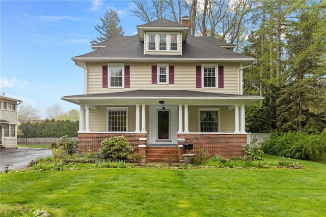 traditional style home with a front lawn, brick siding, a porch, and a chimney