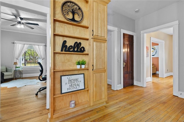 hall with light wood-style floors, baseboards, and ornamental molding