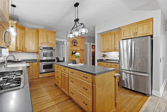 kitchen featuring backsplash, dark countertops, appliances with stainless steel finishes, and a sink