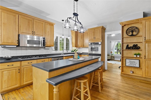 kitchen featuring dark countertops, stainless steel appliances, a breakfast bar area, and light wood-type flooring