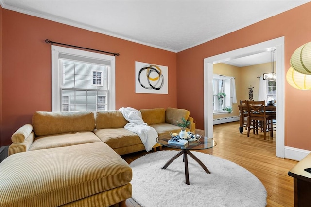 living area with crown molding, baseboards, baseboard heating, and light wood finished floors