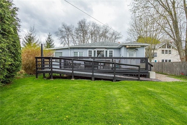 back of house with a yard, a deck, a shingled roof, and fence