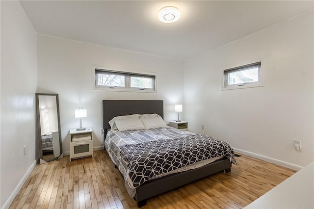 bedroom featuring baseboards, light wood-type flooring, and multiple windows