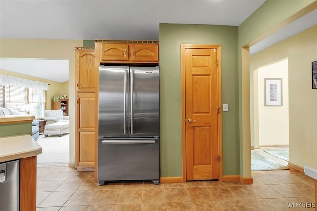 kitchen with high end refrigerator, light countertops, baseboards, and light tile patterned floors