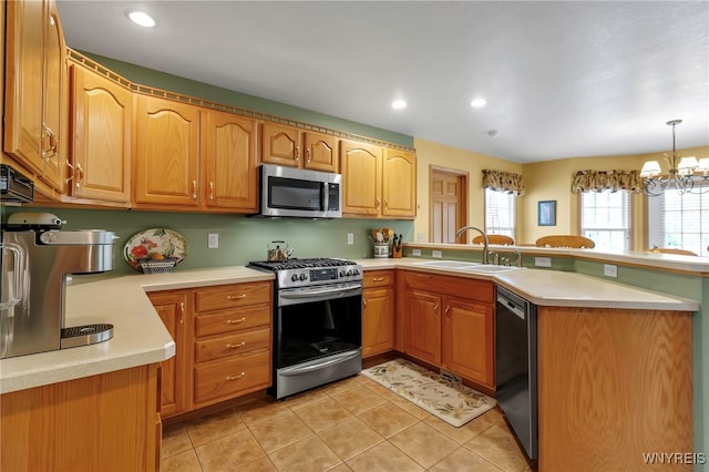 kitchen with a peninsula, light countertops, appliances with stainless steel finishes, and a sink