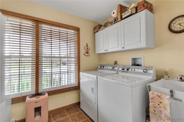 washroom featuring baseboards, a sink, tile patterned floors, washer and clothes dryer, and cabinet space