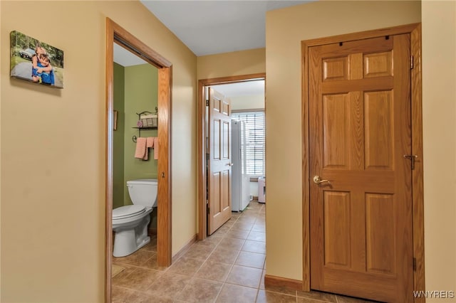 hallway featuring baseboards and light tile patterned flooring