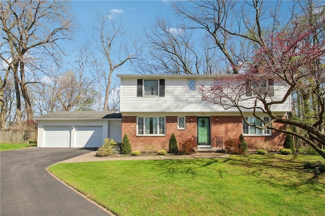 colonial inspired home featuring an attached garage, fence, a front lawn, brick siding, and driveway
