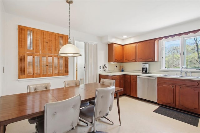 kitchen featuring light countertops, a sink, brown cabinetry, pendant lighting, and dishwasher