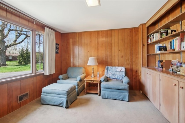 living area featuring light colored carpet, wooden walls, and visible vents