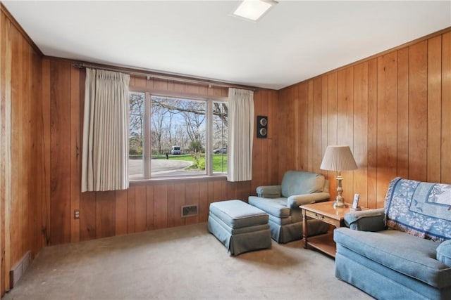 living area featuring wood walls, carpet, and visible vents