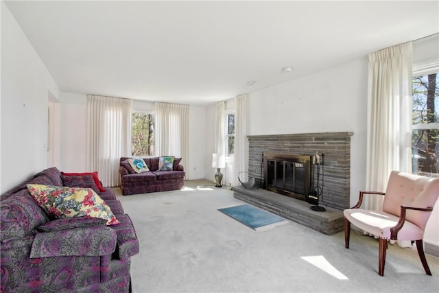carpeted living area featuring a stone fireplace