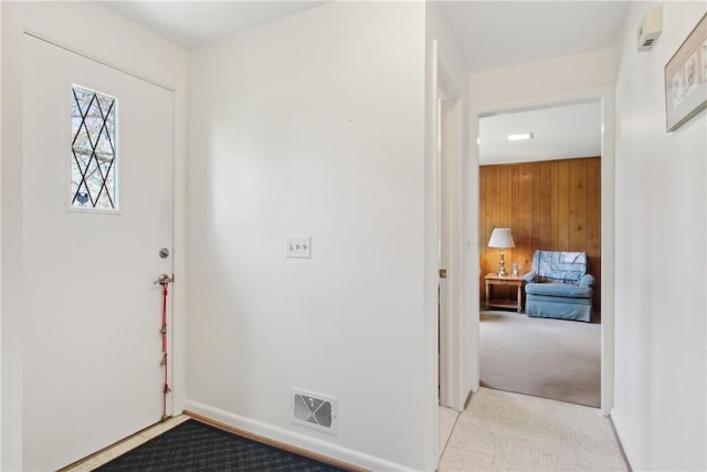 entrance foyer featuring wooden walls, carpet flooring, and visible vents