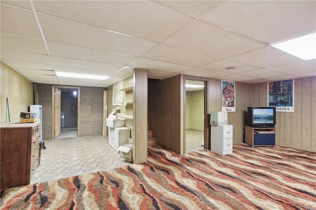 carpeted bedroom featuring wood walls and a paneled ceiling