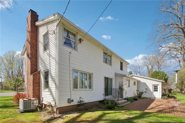 rear view of property featuring a yard, a chimney, and central AC unit