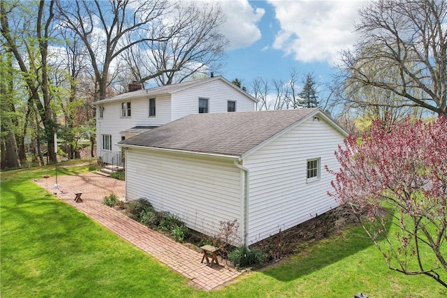 view of property exterior featuring a yard, a chimney, and roof with shingles