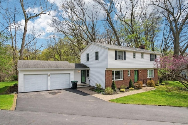 view of front of house with a chimney, driveway, brick siding, an attached garage, and a front lawn