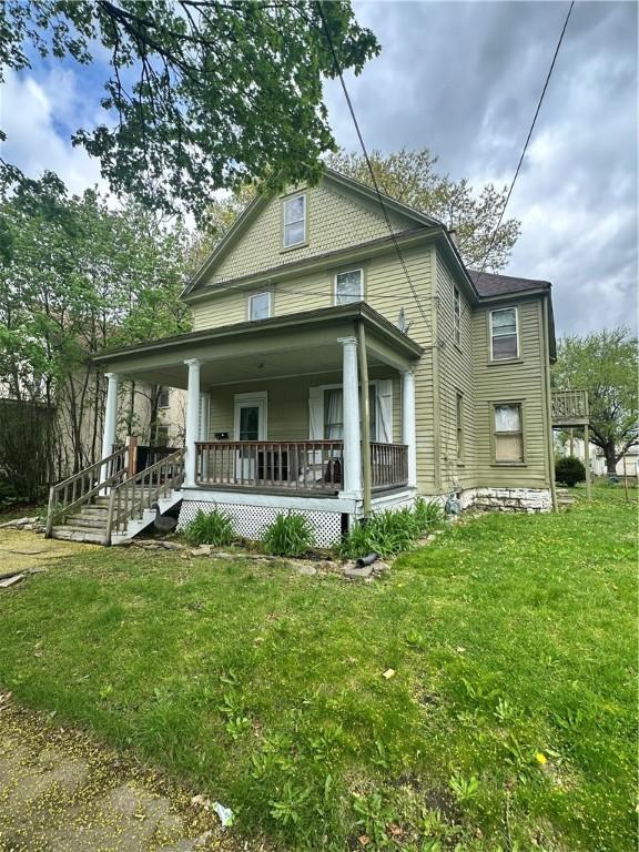 rear view of property featuring a lawn and covered porch